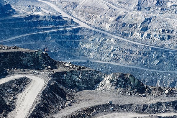 A terraced open-pit mine with winding roads and exposed rock layers