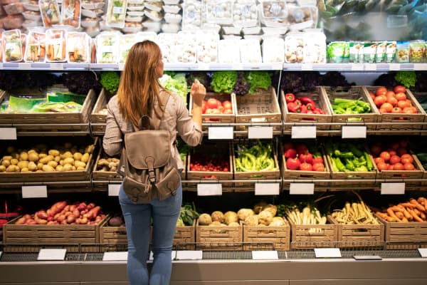Shopper selecting fresh bell peppers from the produce section of a grocery store.