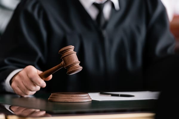 A judge in a black robe holds a wooden gavel, representing the recent appeals court decision that shut down J&J's talc bankruptcy strategy.