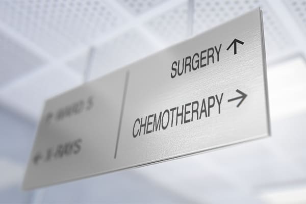 A ceiling sign in a hospital hallway points one direction for chemotherapy and another direction for surgery, symbolizing the quandary posed by the study covered in this post.