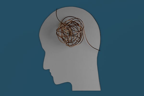 This image depicts a light gray silhouette of a person's head and neck set against a dark gray background. A ball of tangled yarn sits atop the silhouette where the brain would be, metaphorically depicting the mental challenges of chemo brain.