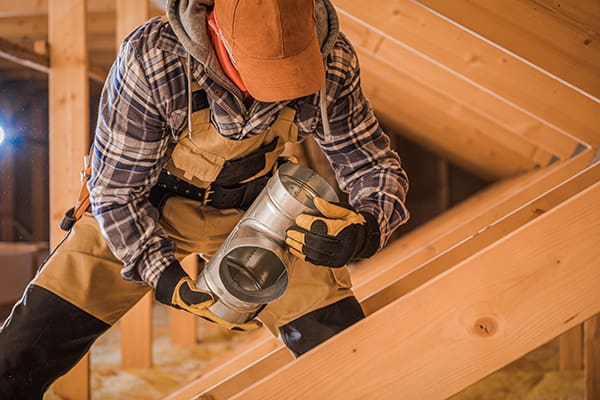 Photo of an HVAC worker handling air ducts. Connectors once used asbestos.