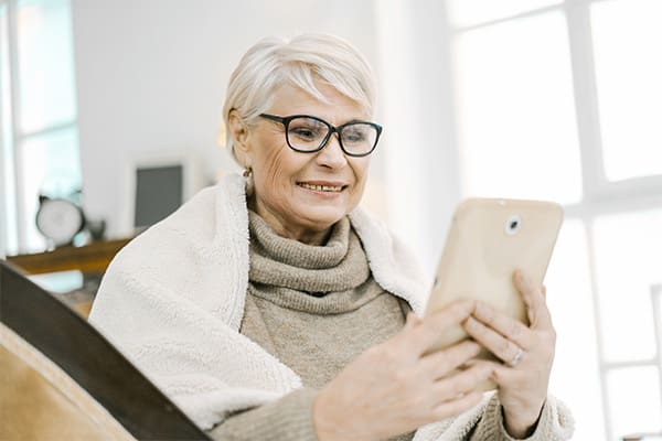 A cancer patient reading a book on her tablet while waiting for treatment.