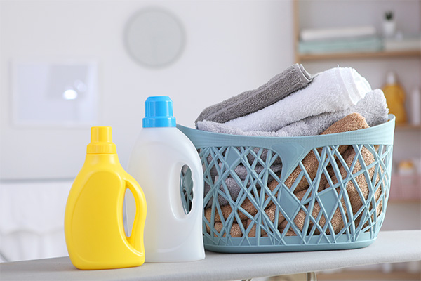 A photo of a laundry service gift: nicely folded towels, laundry detergent and fabric softener.