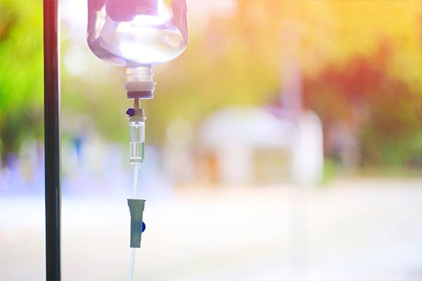 A bag of mesothelioma immunotherapy drugs hangs from an IV stand in front of a window.