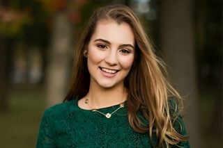 A photo of 2023 Mesothelioma Scholarship winner, Isabella Toth. She has long, dark blonde hair and is wearing a dark green lace shirt.