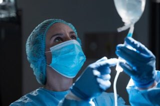 A nurse injects an immunotherapy drug into a hanging drug delivery bag used for intravenous cancer treatment.