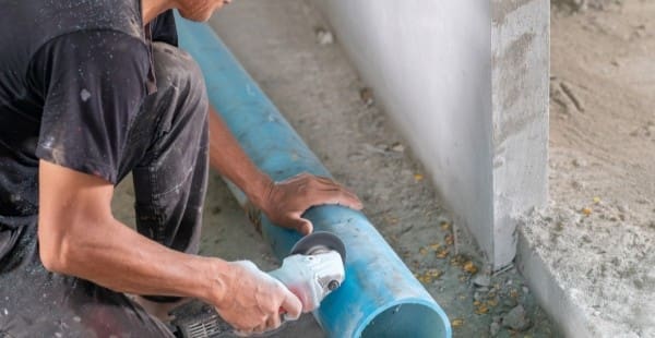 Construction worker cutting pipe in commercial building, highlighting potential occupational asbestos exposure